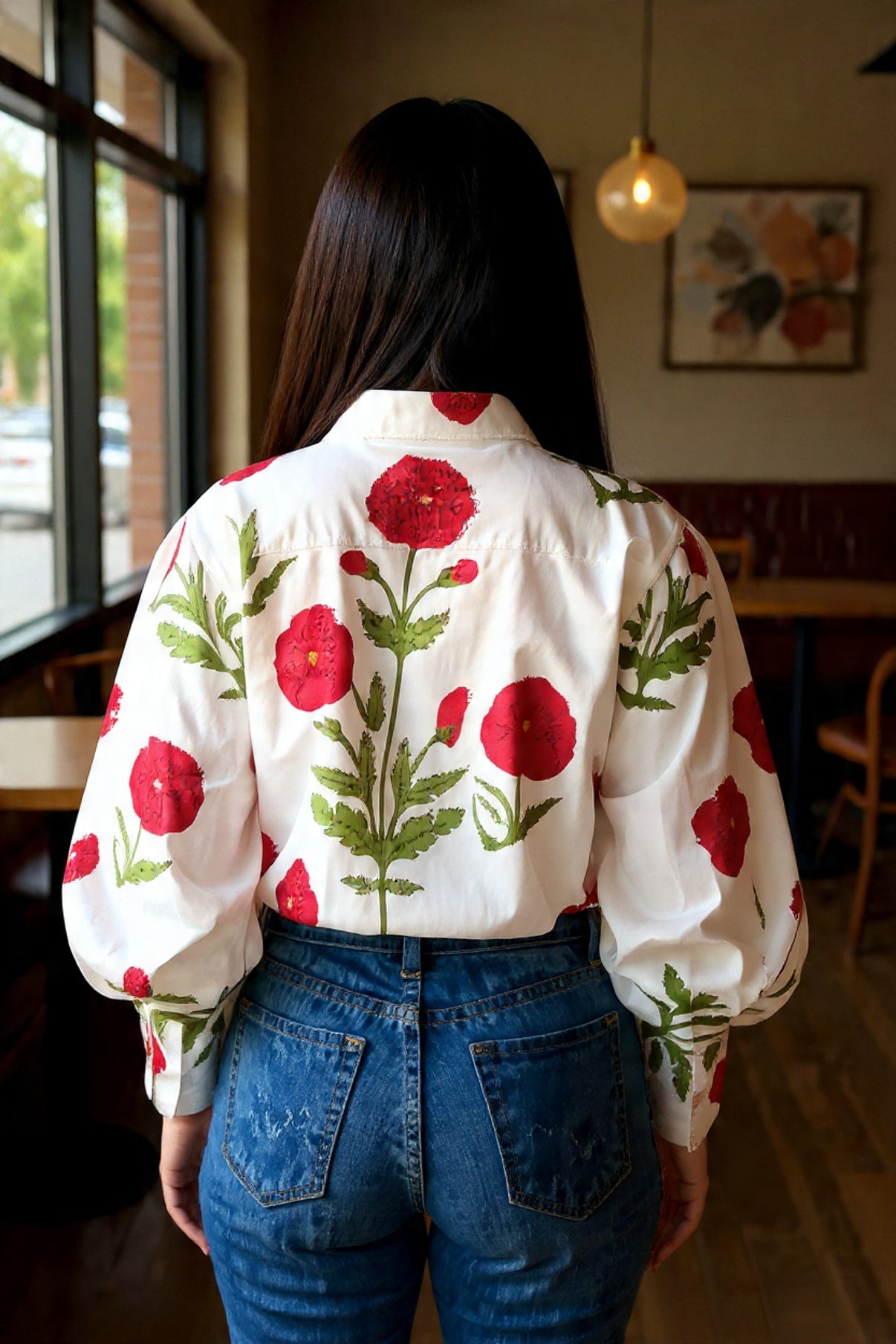 Person wearing a white blouse with red floral patterns in a casual setting.