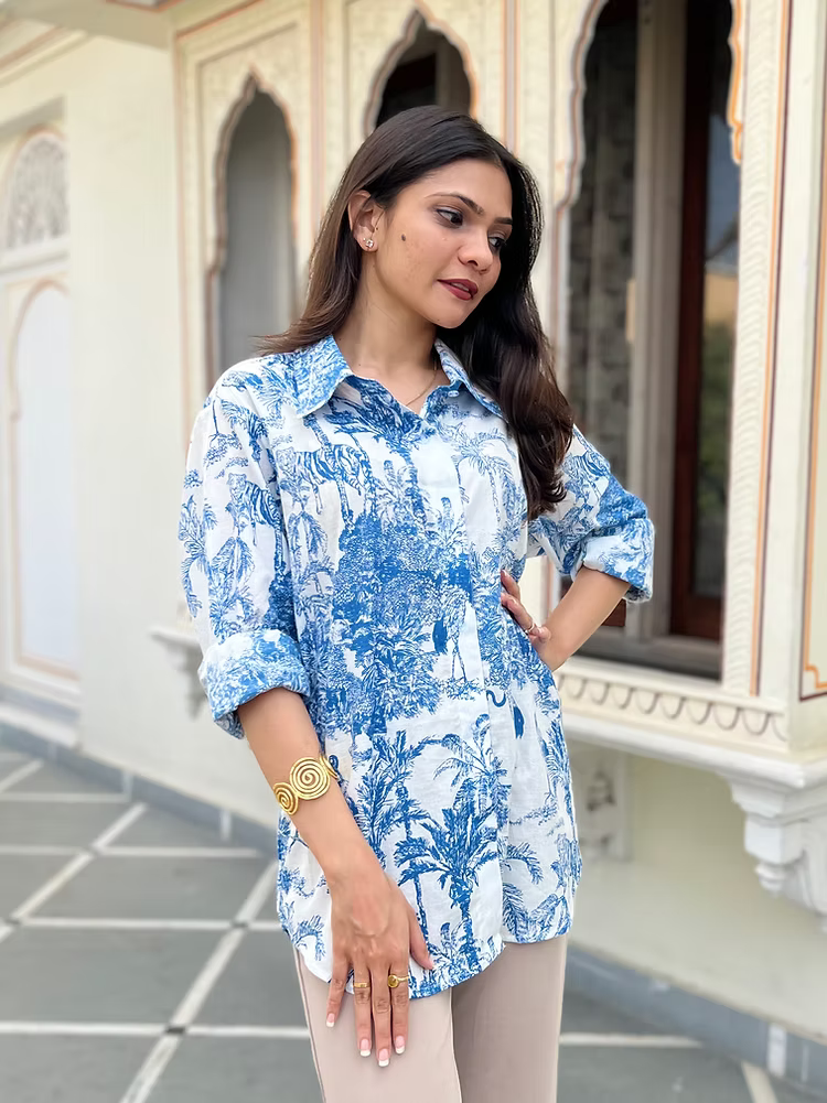 Woman wearing a blue and white patterned shirt standing in front of an ornate building.