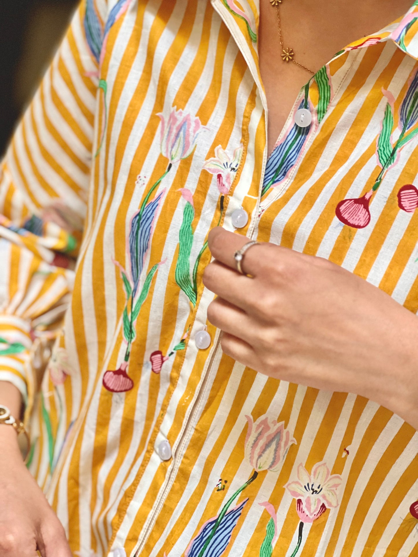 Close-up of a person wearing a yellow and white striped shirt with floral patterns.