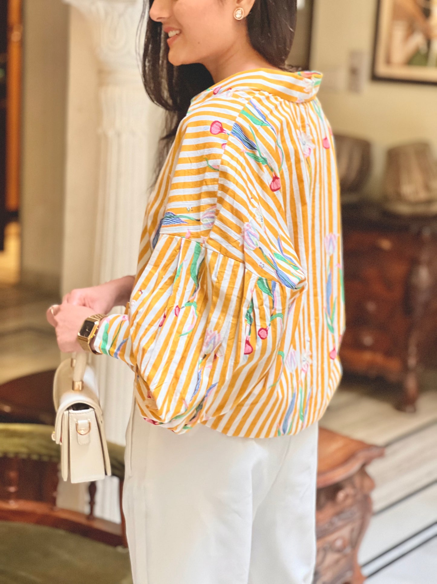 Woman wearing a yellow striped shirt with colorful patterns indoors.