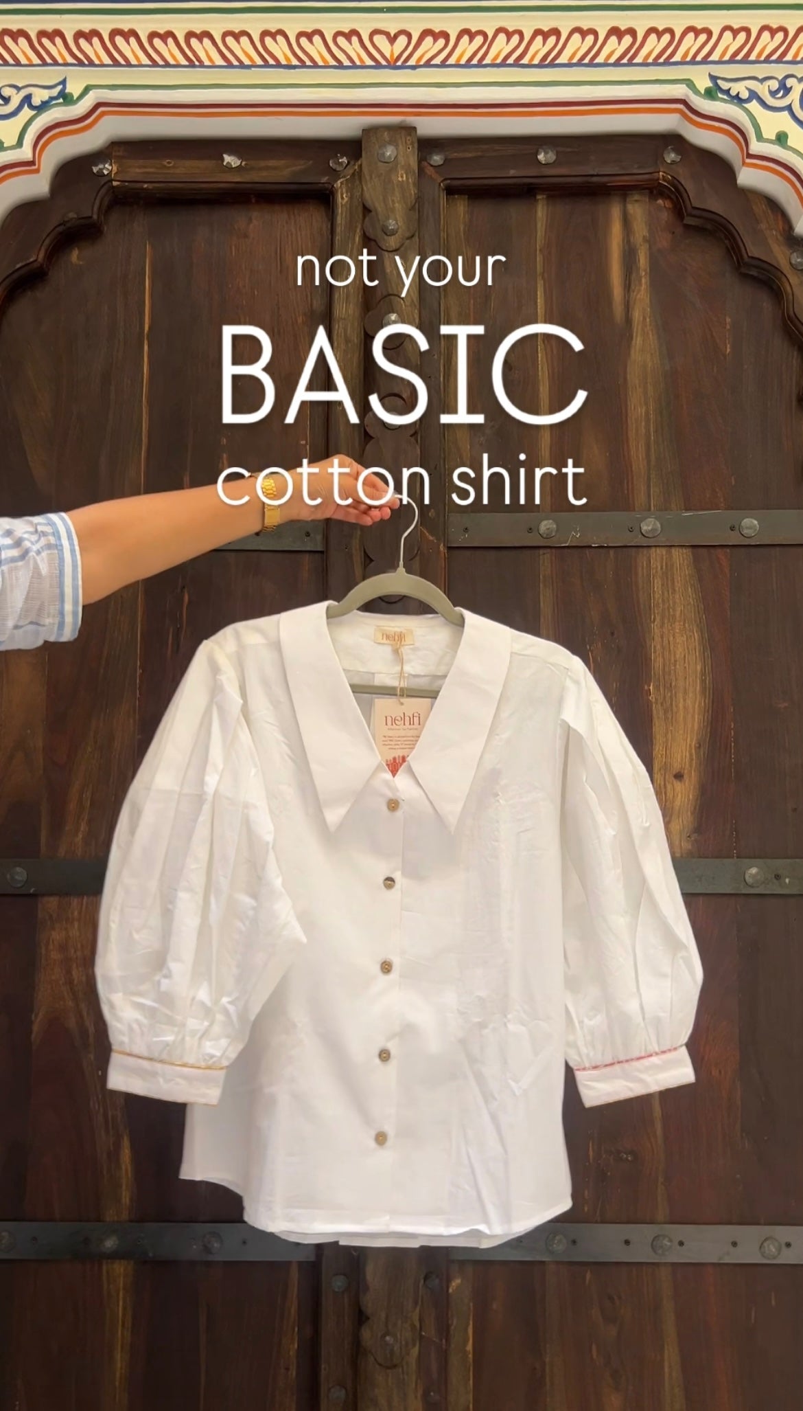 White cotton shirt on a hanger with text 'not your BASIC cotton shirt' against a wooden door background