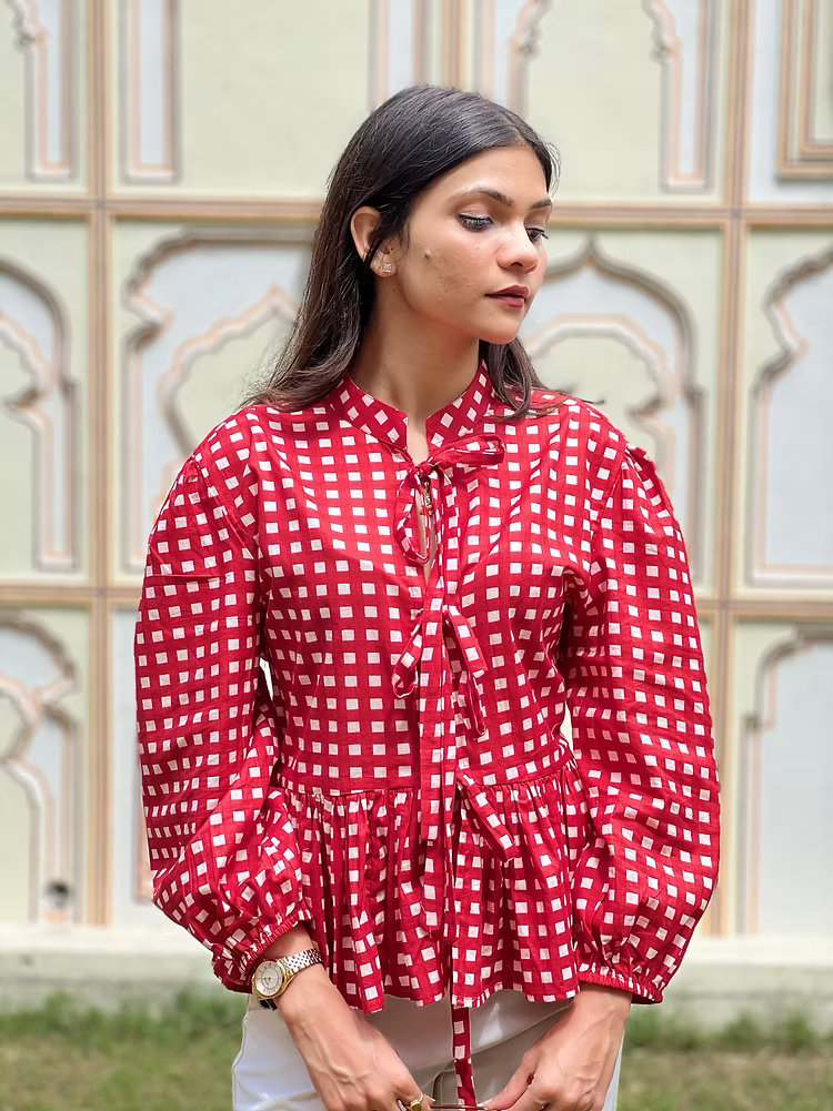 Woman wearing a red and white checkered blouse with a decorative background