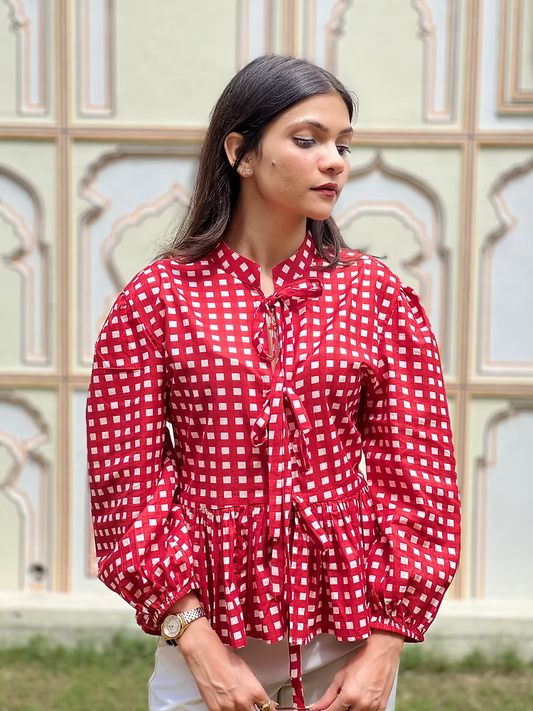 Woman wearing a red and white checkered blouse with a decorative background