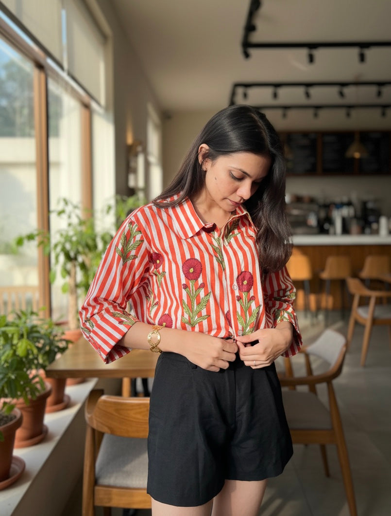 Woman in a red and white striped shirt with floral patterns in a casual setting